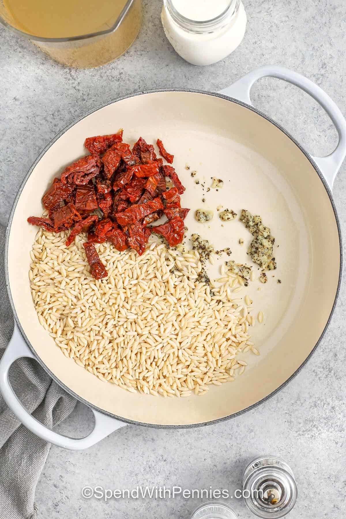 adding ingredients to pan to make Marry Me Chicken Orzo