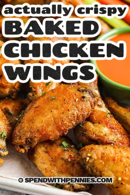 These crispy baked chicken wings are juicy inside with golden, crackly skin on the outside. The secret is patting the wings very dry, coating with flour and baking powder, then chilling uncovered so the skin dries out. Bake them on a rack so hot air circulates all around, then finish with a quick broil if you want even more crunch. Serve them dry with ranch dressing or toss them in buffalo sauce right before serving. #spendwithpennies close up of Actually Crispy Oven Baked Wings with writing