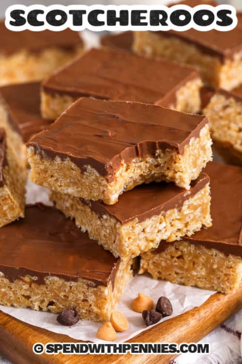 This Scotcheroos recipe creates soft, chewy cereal bars coated in a silky blend of chocolate and butterscotch. The peanut butter syrup comes together quickly on the stovetop and mixes easily with crisp cereal for a perfect texture. These bars are ideal for potlucks, bake sales, or simple weeknight treats. They set beautifully and slice cleanly, making them a reliable no-bake dessert for any occasion. #spendwithpennies Scotcheroos on a wooden board with parchement paper with a bite out of one and a title