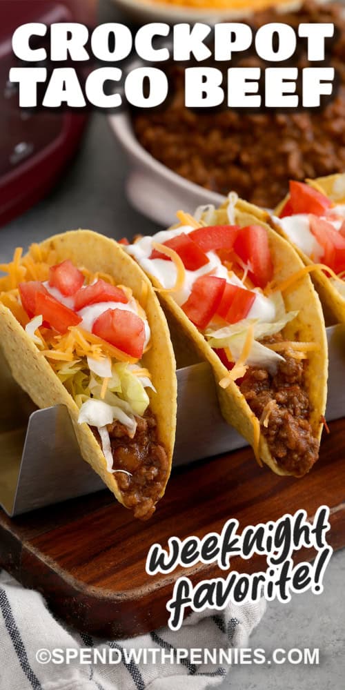 Closeup of a weeknight favorite, Crockpot Taco Beef in taco shells with all the fixings and a title.