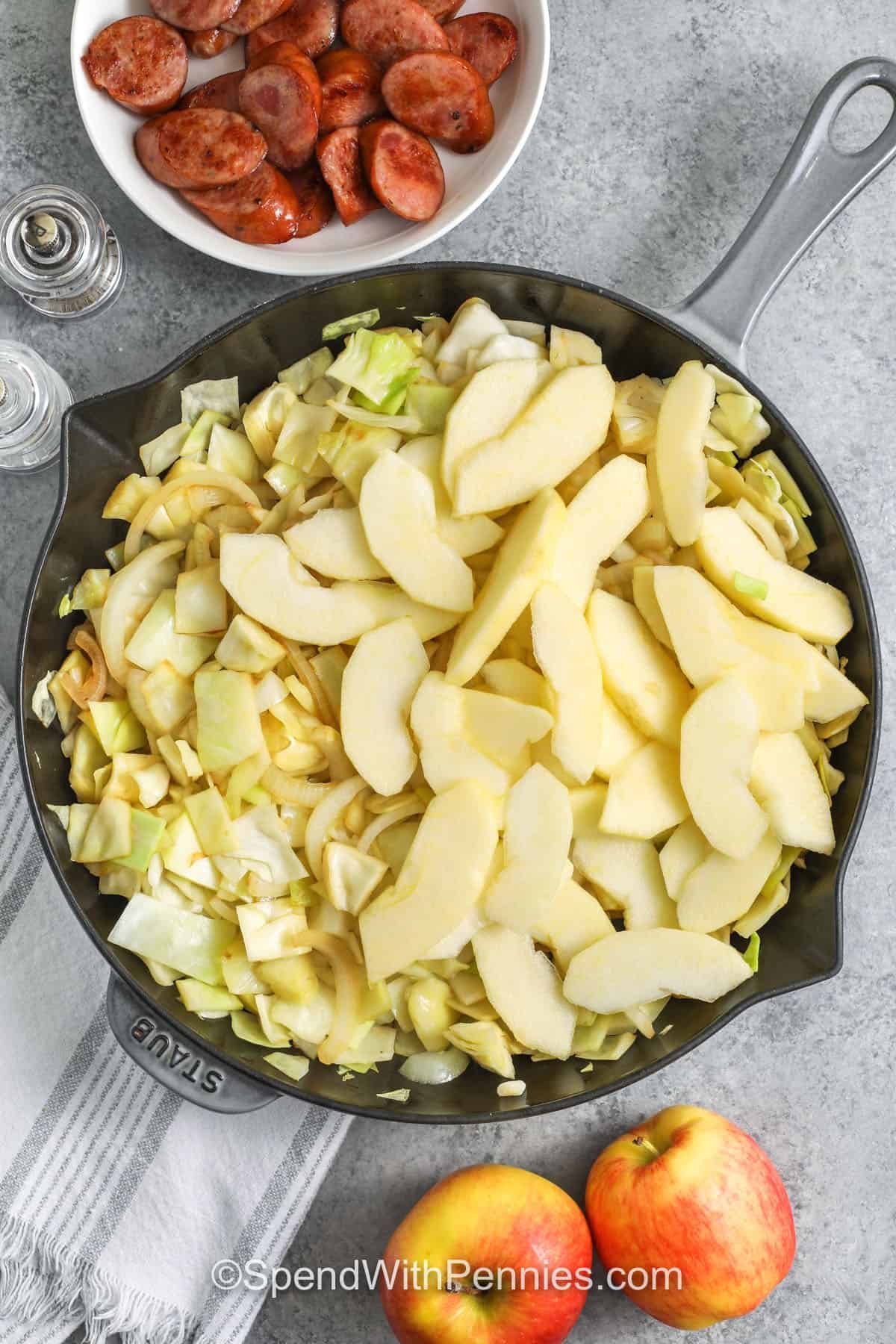 adding apples to pan to make Sausage, Cabbage, and Apple Skillet
