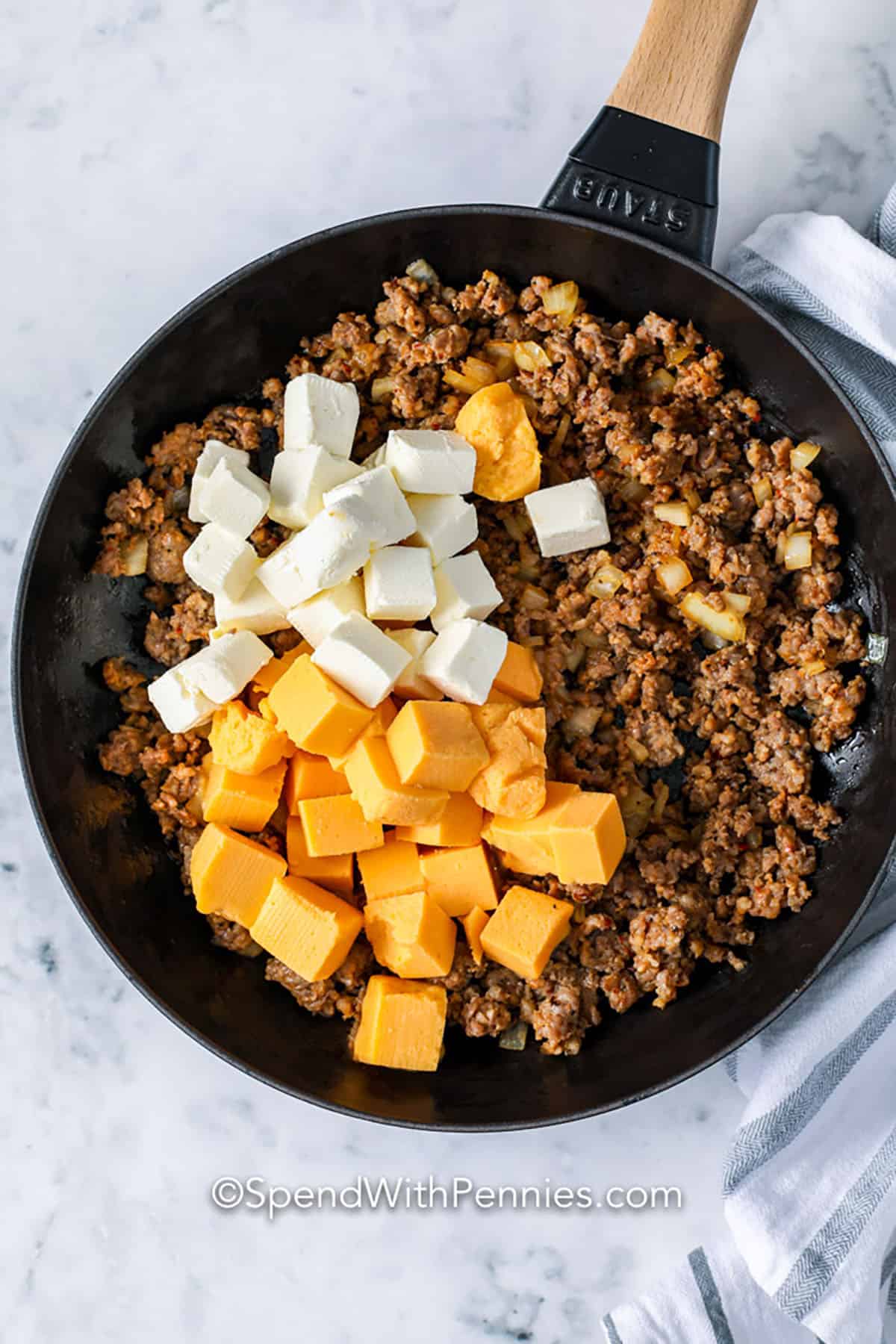 adding cheese to beef and onions to make Sausage Cheese Dip