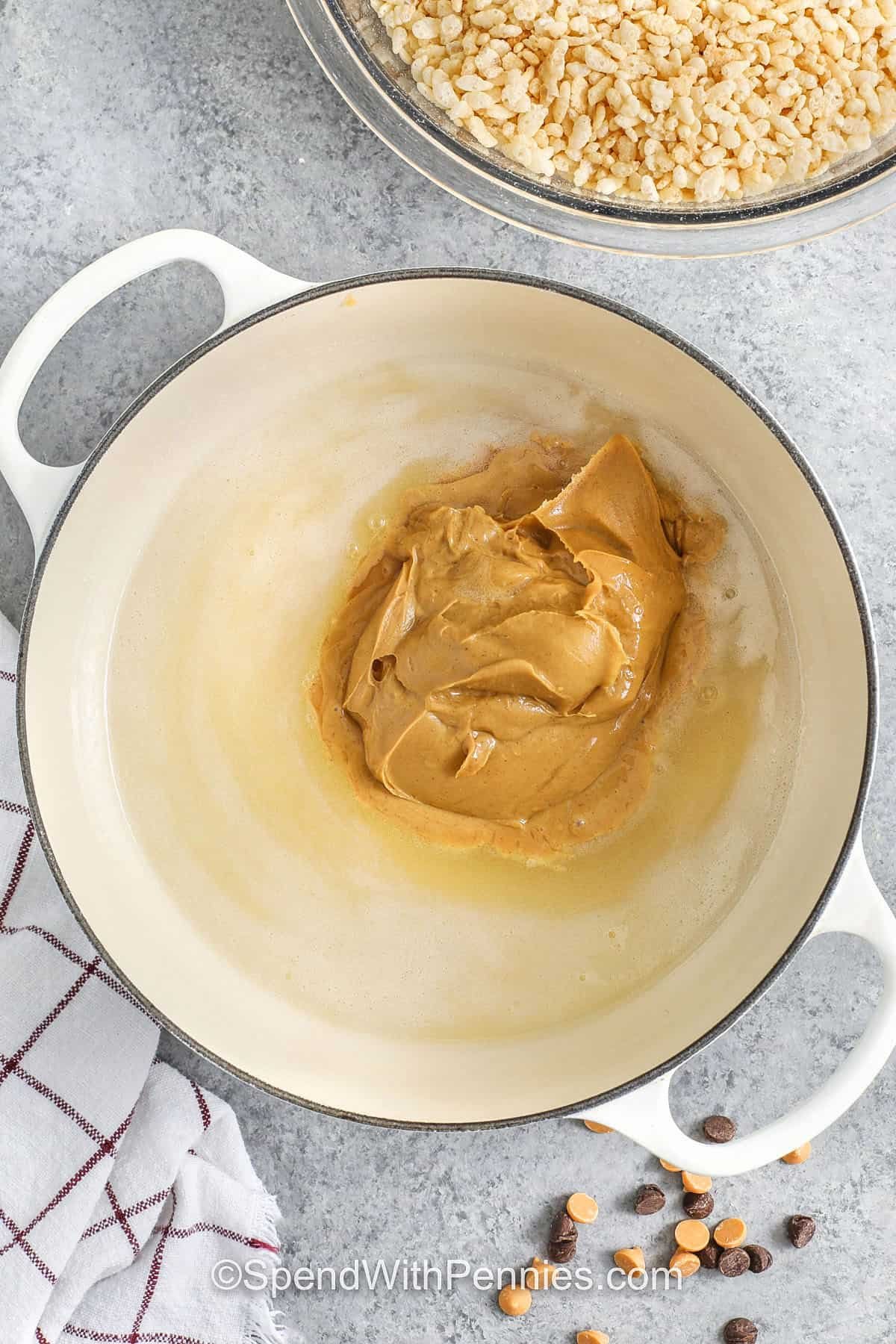 Make these Scotcheroos for an effortless dessert that blends crisp cereal with a smooth peanut butter mixture. The chocolate-butterscotch topping creates a rich layer that sets perfectly over the chewy base. They are easy to prepare with everyday ingredients and stay fresh for days. Perfect for gatherings, after-school snacks, or weekend treats, these bars offer classic flavor and dependable results. #spendwithpennies adding peanut butter to oil and sugar mixture to make Scotcheroos