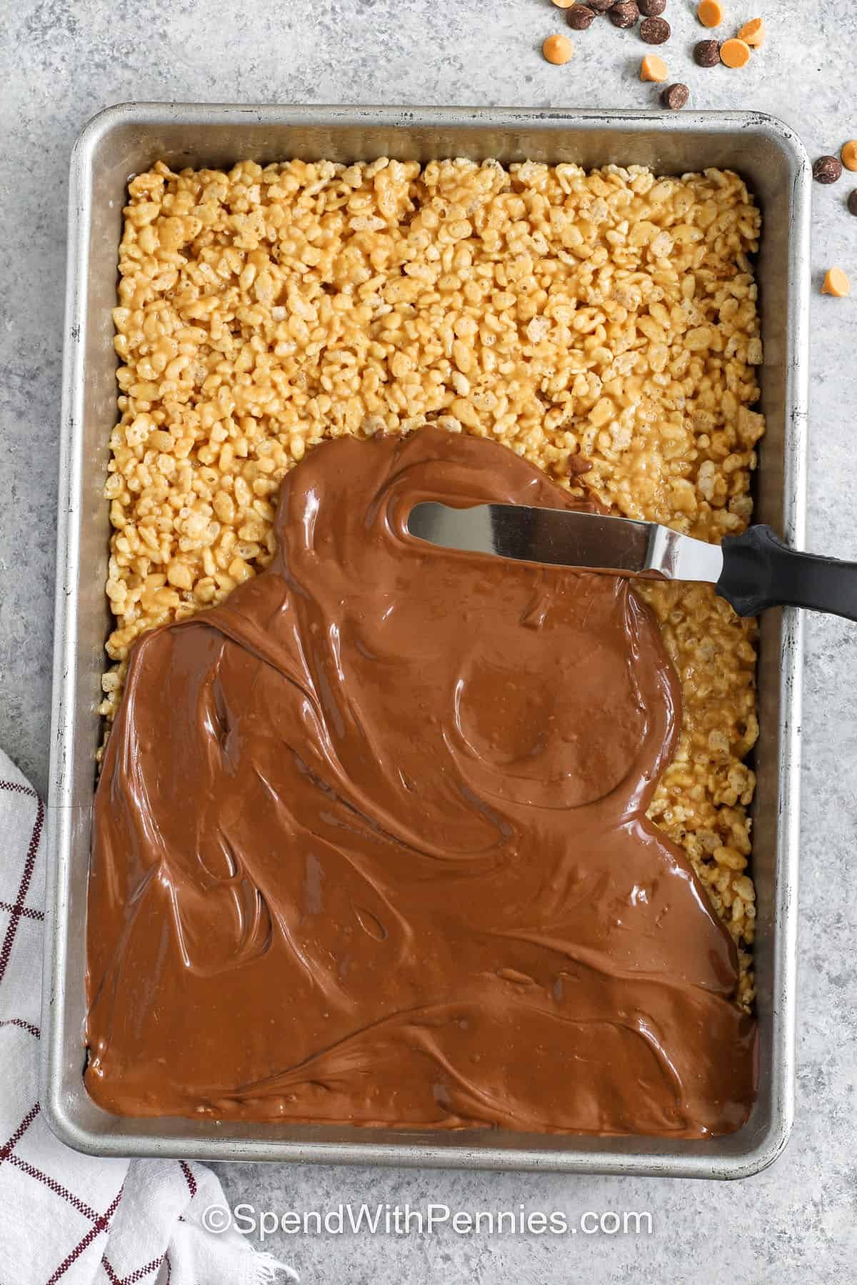 Scotcheroos are an easy choice when you need a dessert that comes together fast and tastes incredible. The chewy peanut butter base mixes with cereal for great texture, and the chocolate-butterscotch topping adds a sweet, creamy finish. These bars require minimal equipment and no baking, making them a go-to option for busy days. They slice neatly and store well, ideal for make-ahead treats. #spendwithpennies adding chocolate on top of peanut butter , butterscotch and puffed rice cereal to make Scotcheroos