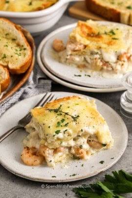 Seafood Lasagna slices on plates with garlic toast