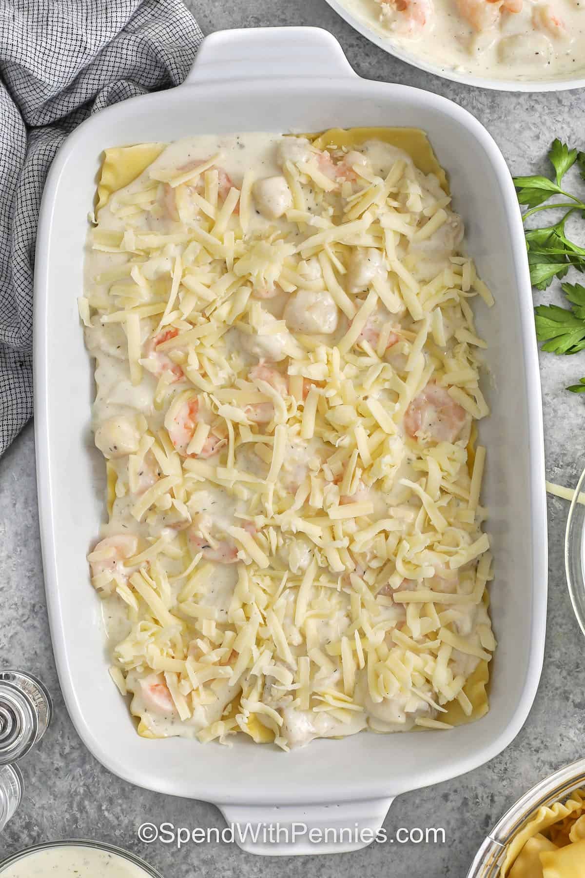 adding lasagna noodles , seafood with sauce and cheese layer to dish to make Seafood Lasagna