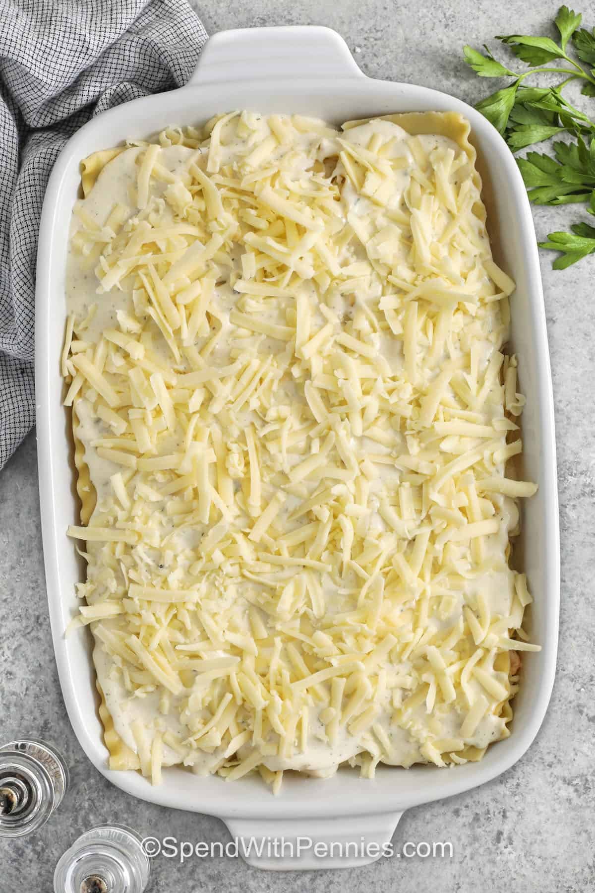 adding sauce and cheese layer on top of lasagna noodles to make Seafood Lasagna