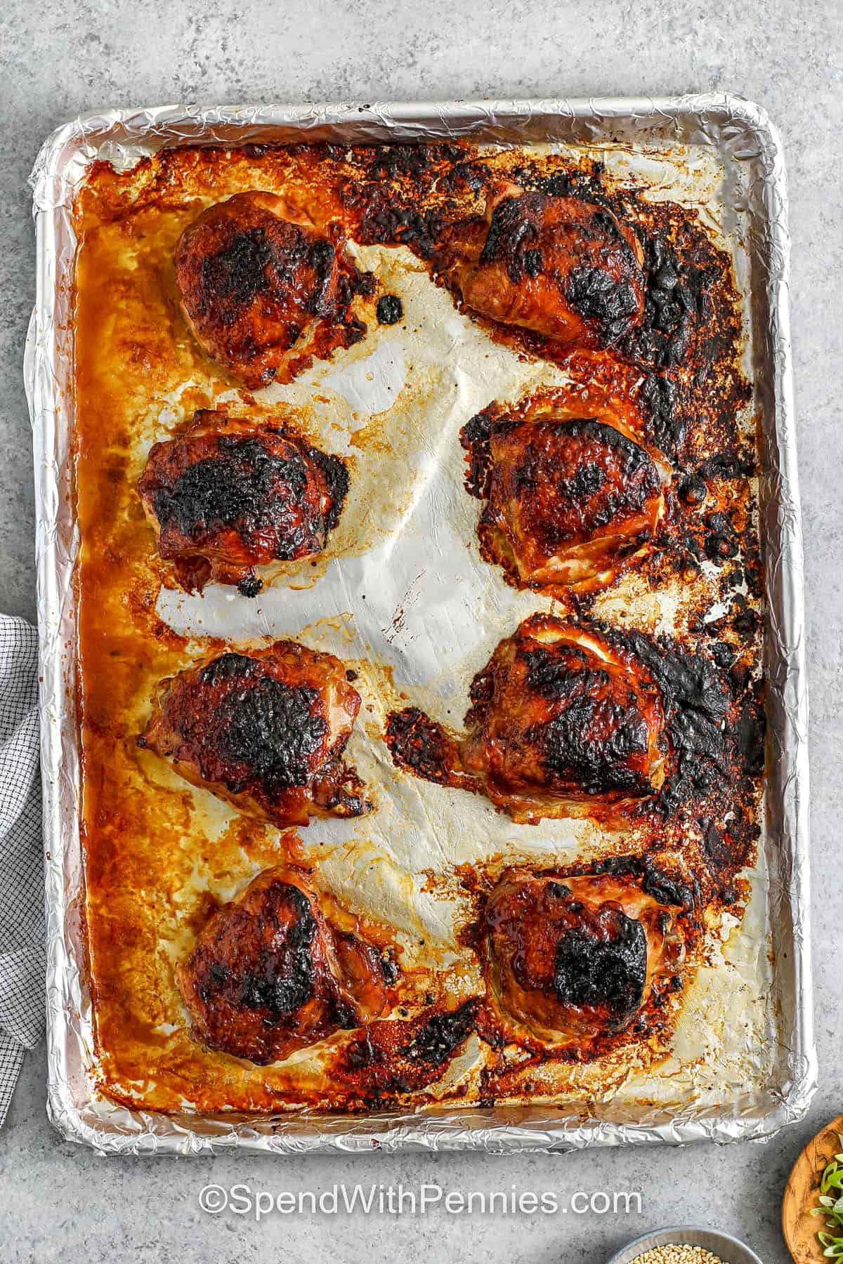 These sticky chicken thighs have a tasty maple garlic sauce that’s super quick to make on the stovetop, and it coats each piece for the best flavor. The combination of Dijon mustard and soy sauce adds savory depth to the sweetness of the maple syrup. With minimal prep and easy cleanup, this dish fits perfectly into a busy schedule while still feeling special enough for a family dinner. Serve with potatoes or steamed vegetables. #spendwithpennies baked sticky chicken thighs on a cookie sheet