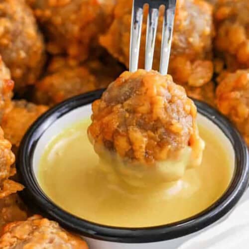 close up of dipping Sausage Balls in sauce