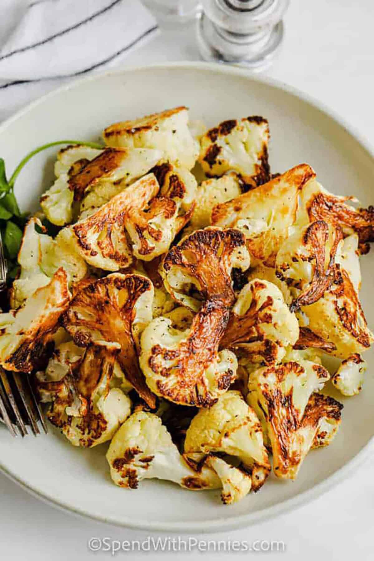 Roasted cauliflower gets irresistibly crisp when it hits a preheated sheet pan. Dry florets well, toss with olive oil, salt, pepper, and optional garlic powder, then place them flat-side down for maximum browning. This easy roasted cauliflower method builds a golden crust without flipping, so the edges caramelize while the centers stay tender. Serve warm or reheat in the oven for extra crunch. #spendwithpennies crispy roasted cauliflower on a plate
