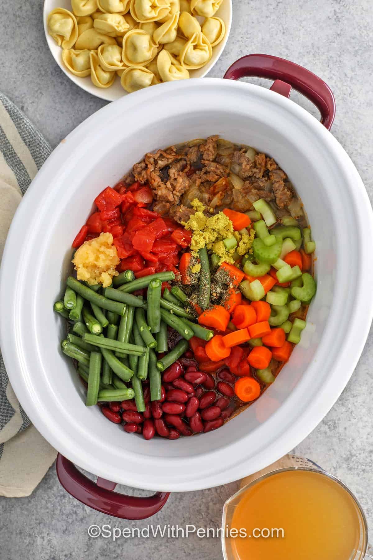 adding veggies to crockpot to make Crockpot Tortellini Soup
