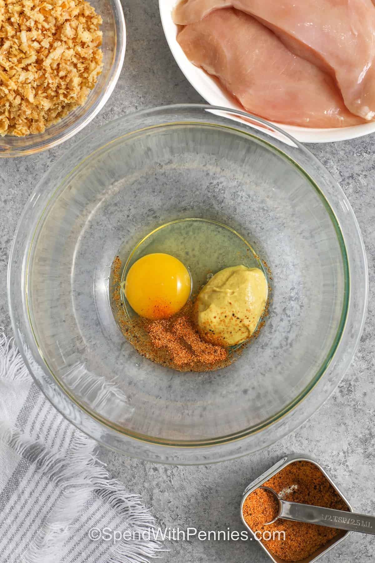 This crunchy French onion chicken is crispy and easy to make. The Dijon egg coating helps the crushed, crispy fried onions stick, creating a golden crust in the oven without extra breading steps. Pound the chicken evenly for consistent cook time, then bake until golden and crispy. Serve with seasoned rice or roasted vegetables for a simple meal, and freeze cooked portions for quick lunches. #spendwithpennies egg dijon and seasoning in a mixing bowl