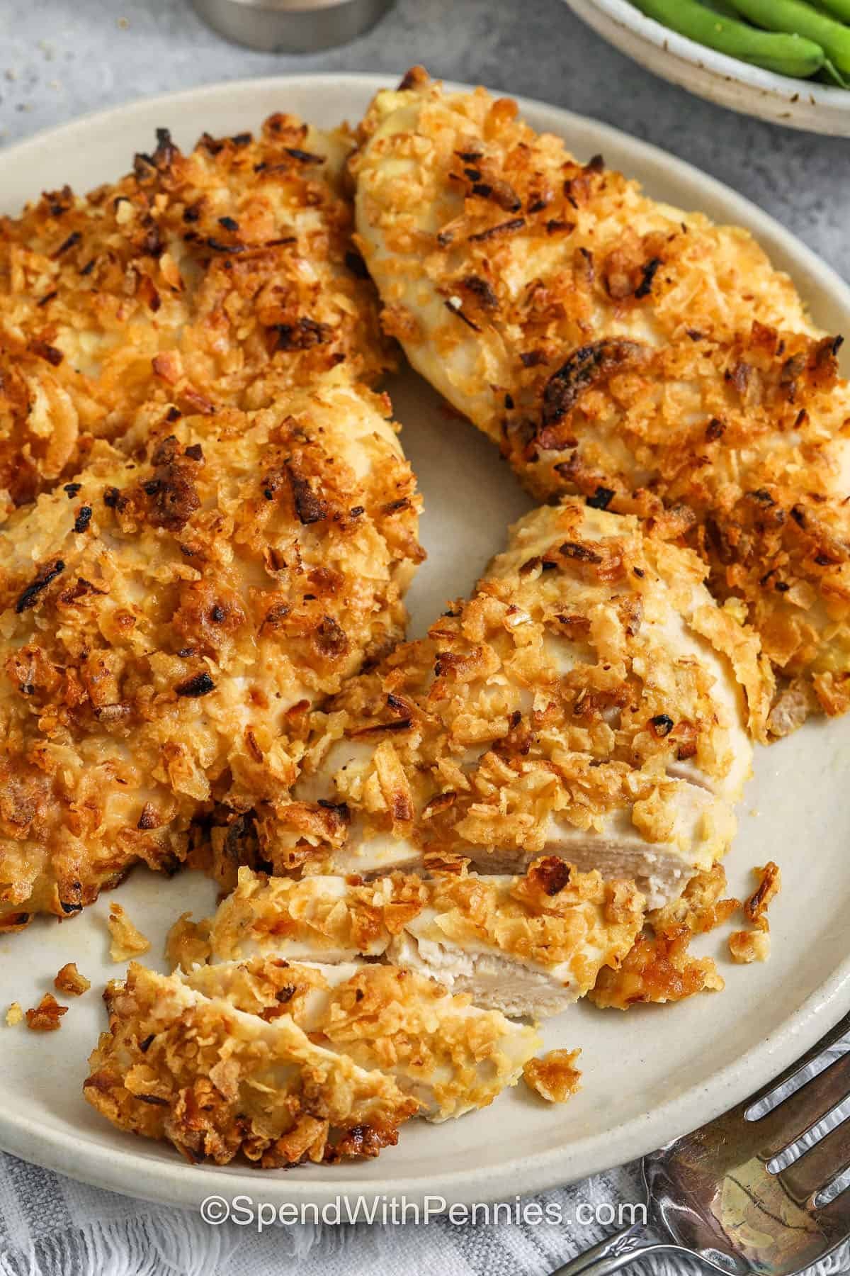 French onion baked chicken is a family-friendly baked chicken breasts recipe with a crisp, savory topping. Crispy fried onions add the crunch and flavor, and Dijon gives the coating a little zing. Bake on a sheet pan until perfectly golden, juicy, and crispy. Pair with mashed potatoes or green beans. #spendwithpennies french onion baked chicken on a plate