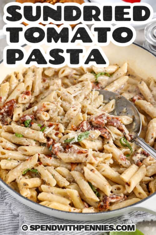This sun dried tomato pasta is a creamy, garlicky dinner made with penne, oil-packed sun-dried tomatoes, herbs, and Parmesan. The sauce is easy to make with sun-dried tomatoes in oil for bold flavor, then half-and-half and Parmesan cheese thicken it. Toss in the pasta and loosen with pasta water until smooth and creamy. Finish with basil or parsley and extra Parmesan for a cozy weeknight meal. #spendwithpennies sun dried tomato pasta in a serving bowl with a spoon and a title