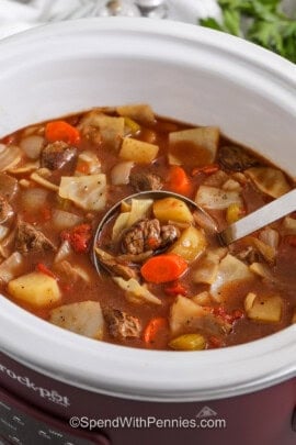 taking a spoonfull of Slow Cooker Beef and Cabbage Stew out of the pot