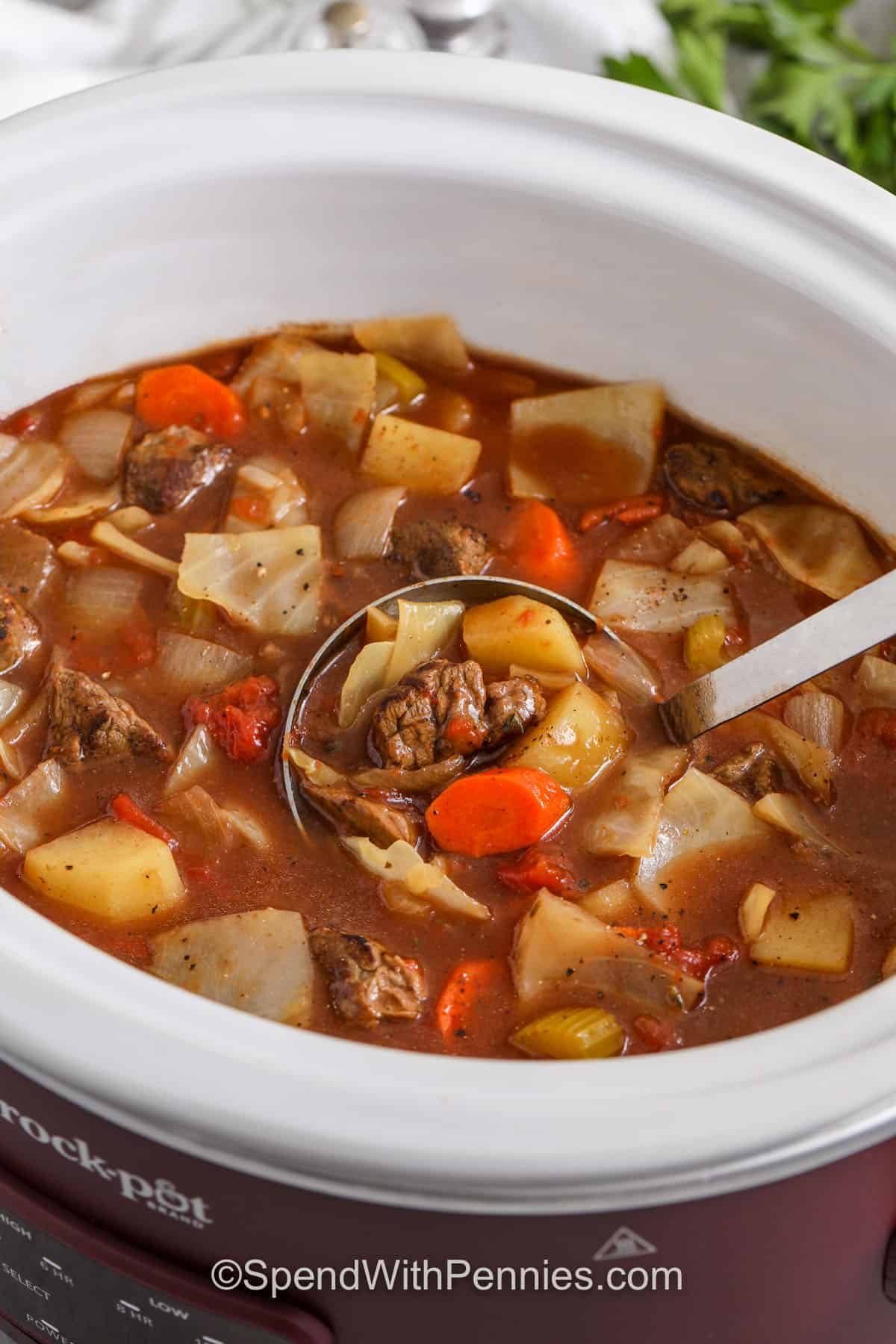 taking a spoonfull of Slow Cooker Beef and Cabbage Stew out of the pot