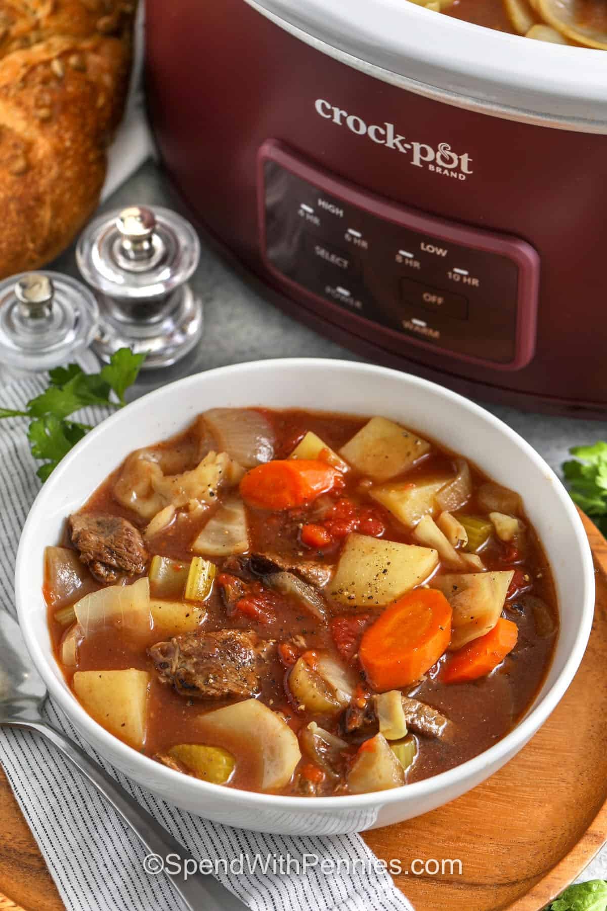 bowl of Slow Cooker Beef and Cabbage Stew with crock pot in the background