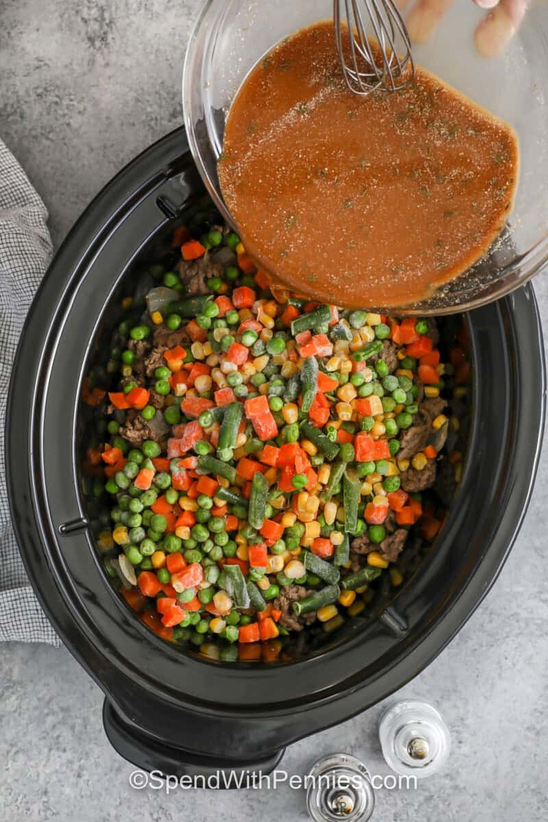 Slow Cooker shepherd's pie is a hearty, family-style dinner with a rich gravy filling and a creamy mashed potato topping. Lean ground beef or lamb keeps the filling from turning greasy, while frozen vegetables add color and texture with zero prep. The sauce comes together fast with gravy mix, broth, Worcestershire, and thyme. Let it rest after cooking for clean slices and scoops. #spendwithpennies adding liquids with seasonings to beef , onions and vegetables to make Slow Cooker Shepherd's Pie
