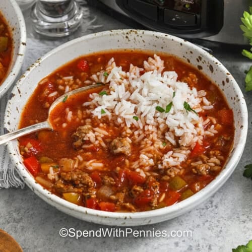 A serving of slow cooker stuffed pepper soup in a bowl with a spoon.