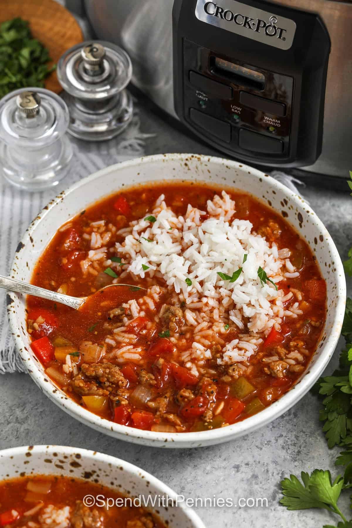 A serving of slow cooker stuffed pepper soup in a bowl with a spoon.