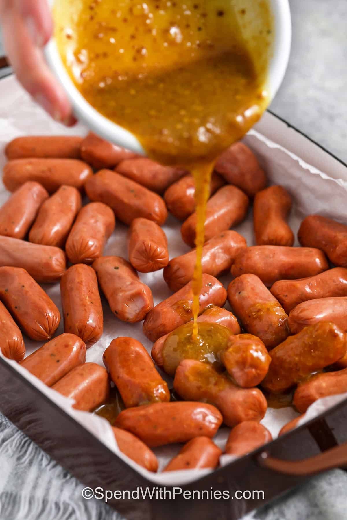 pouring honey mustard sauce over sausages to make Sticky Honey Mustard Sausage