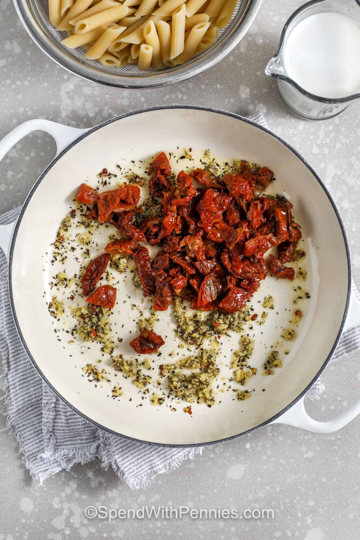 This sun dried tomato pasta is creamy, flavorful, and simple enough for any weeknight. Jarred sun-dried tomato oil adds depth, while garlic, basil, oregano, and Parmesan give it a classic taste. Cornstarch thickens the half-and-half quickly for a smooth sauce that comes together fast. Toss with penne, add pasta water until every noodle is coated, and finish with fresh herbs. #spendwithpennies adding tomatoes to the pan to make sun dried tomato pasta