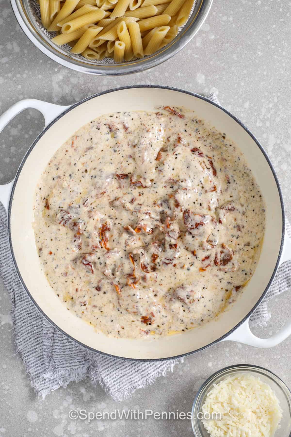 This creamy sun dried tomato pasta is rich, savory, and easy to make. The sauce uses jarred sun-dried tomato oil for depth, plus garlic, basil, oregano, and Parmesan for a classic flavor. Half-and-half thickens quickly with cornstarch, so the sauce is smooth and comes together quickly. Toss with penne and add pasta water until the noodles are coated perfectly, then garnish with fresh herbs. #spendwithpennies making the sauce to make sun dried tomato pasta