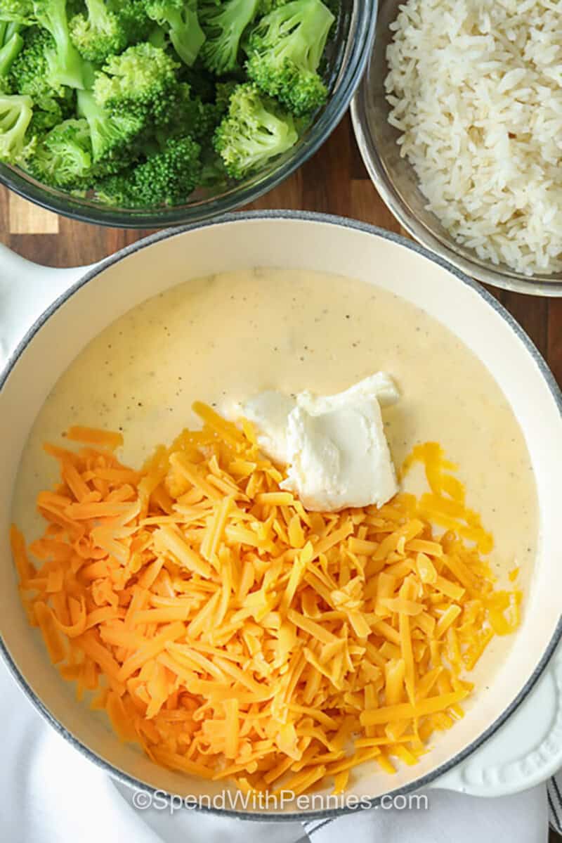 adding cheese to milk and flour in a pot to make Broccoli Rice Casserole from Scratch