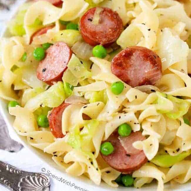 Cabbage and Noodles in a bowl with peas and sausage topped with pepper