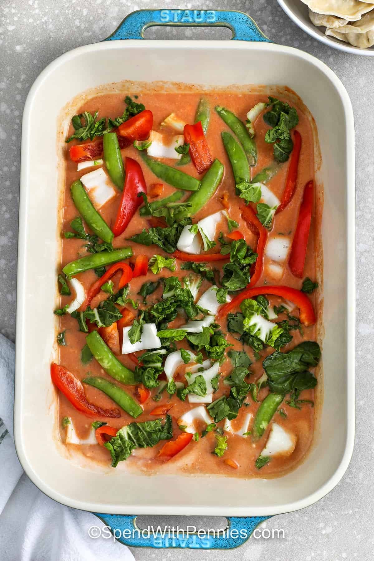 adding vegetables to dish to make Dumpling Bake