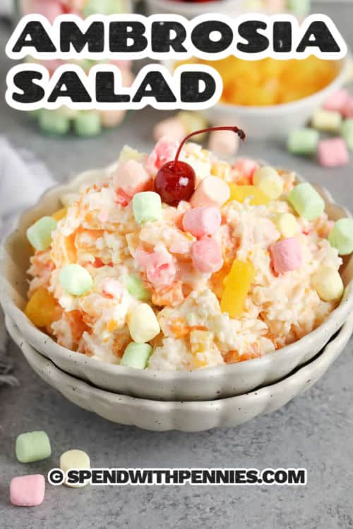 If you love 5 cup salad, this ambrosia salad keeps it classic and colorful. Coconut and marshmallows sweeten a tangy base while pineapple and mandarins add juicy bites in every scoop. Use Greek yogurt for a thicker option or sour cream for traditional flavor. Chill the bowl for several hours so it sets up fluffy, and the fruit stays nicely suspended throughout. #spendwithpennies bowl of Ambrosia Salad with a cherry on top