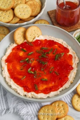 pepper jelly cheese dip in a gray bowl with two crackers