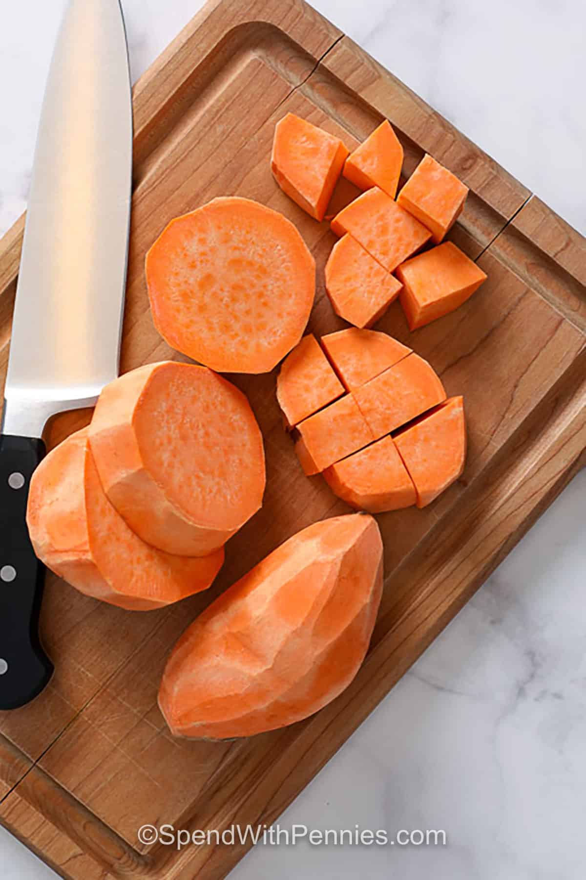 These roasted sweet potatoes are a dependable sheet pan side with caramelized edges and a tender center. Sweet potato cubes are tossed with olive oil, then seasoned savory with garlic powder or turned cozy-sweet with cinnamon. Roasting helps the natural sweetness deepen while the edges brown. Serve them with chicken or pork, or chill leftovers for salads and grain bowls. #spendwithpennies a chopped up sweet potato on a cutting board