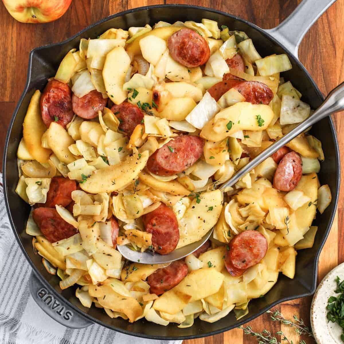 pan of Sausage, Cabbage, and Apple Skillet with a spoon