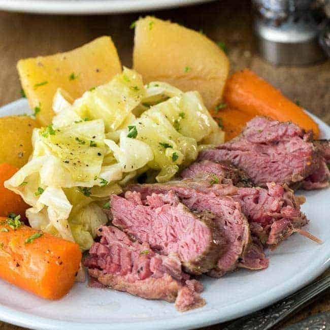 Corned beef and cabbage with potaots and carrots on a white plate