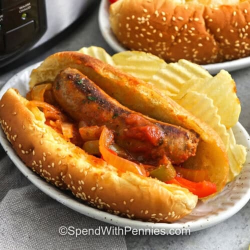 plated hot dog buns with Slow Cooker Sausage and Peppers and chips on the side