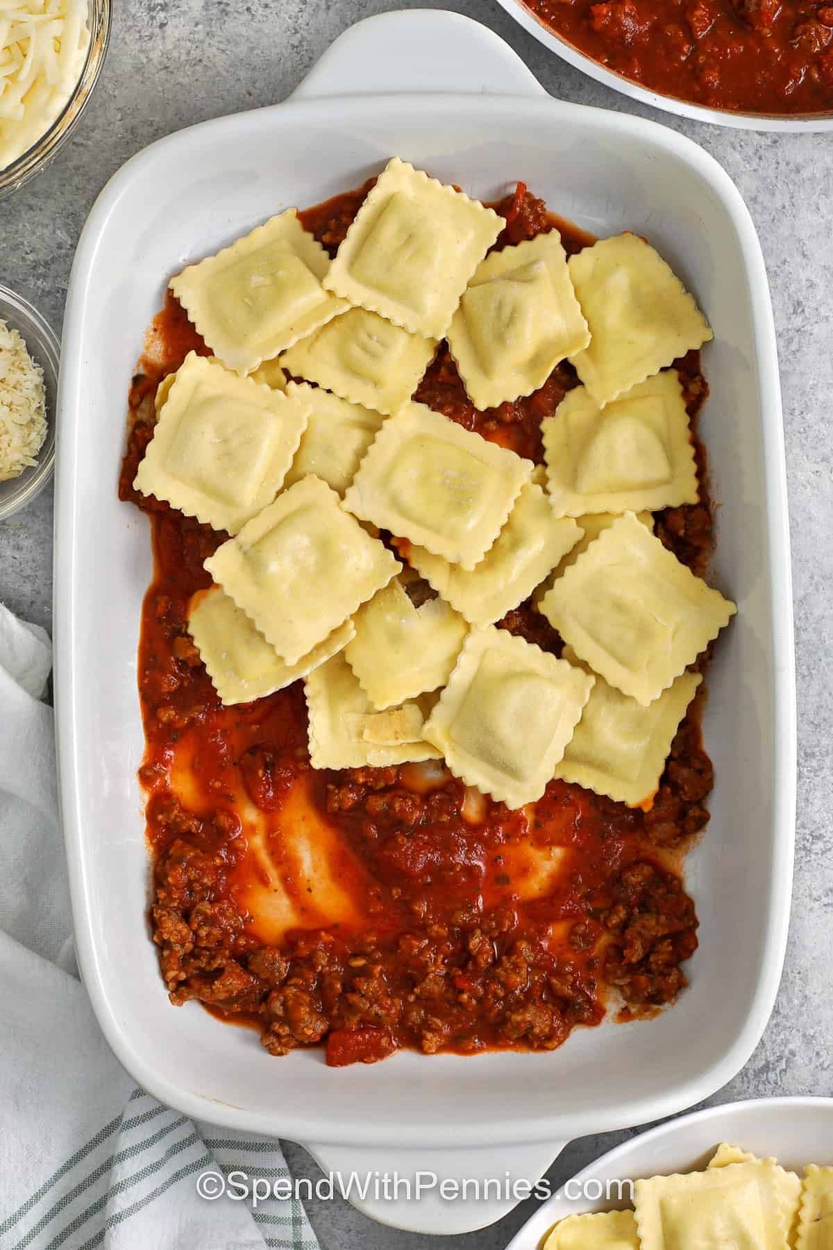adding raviolis to dish with meat sauce on the bottom to make Ravioli Lasagna
