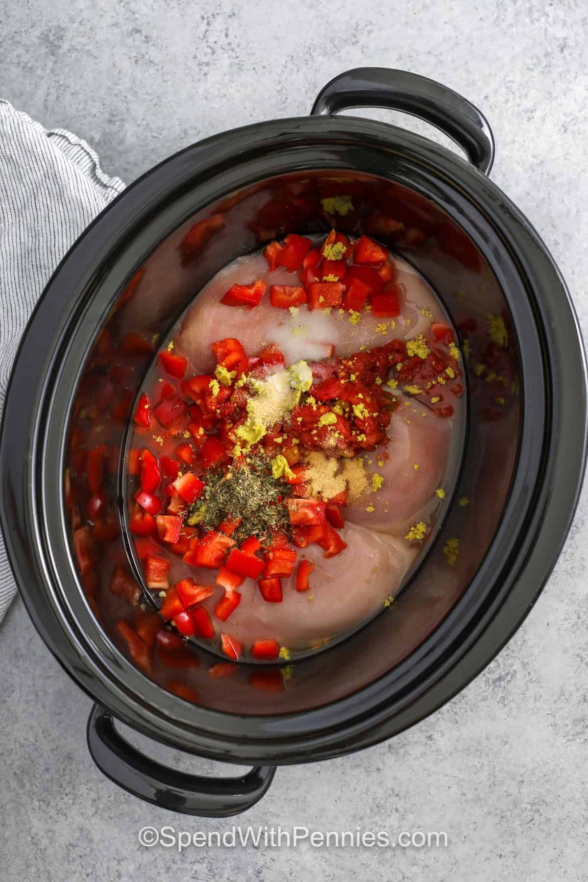 adding peppers and seasonings to chicken to make Crockpot Chicken Spaghetti