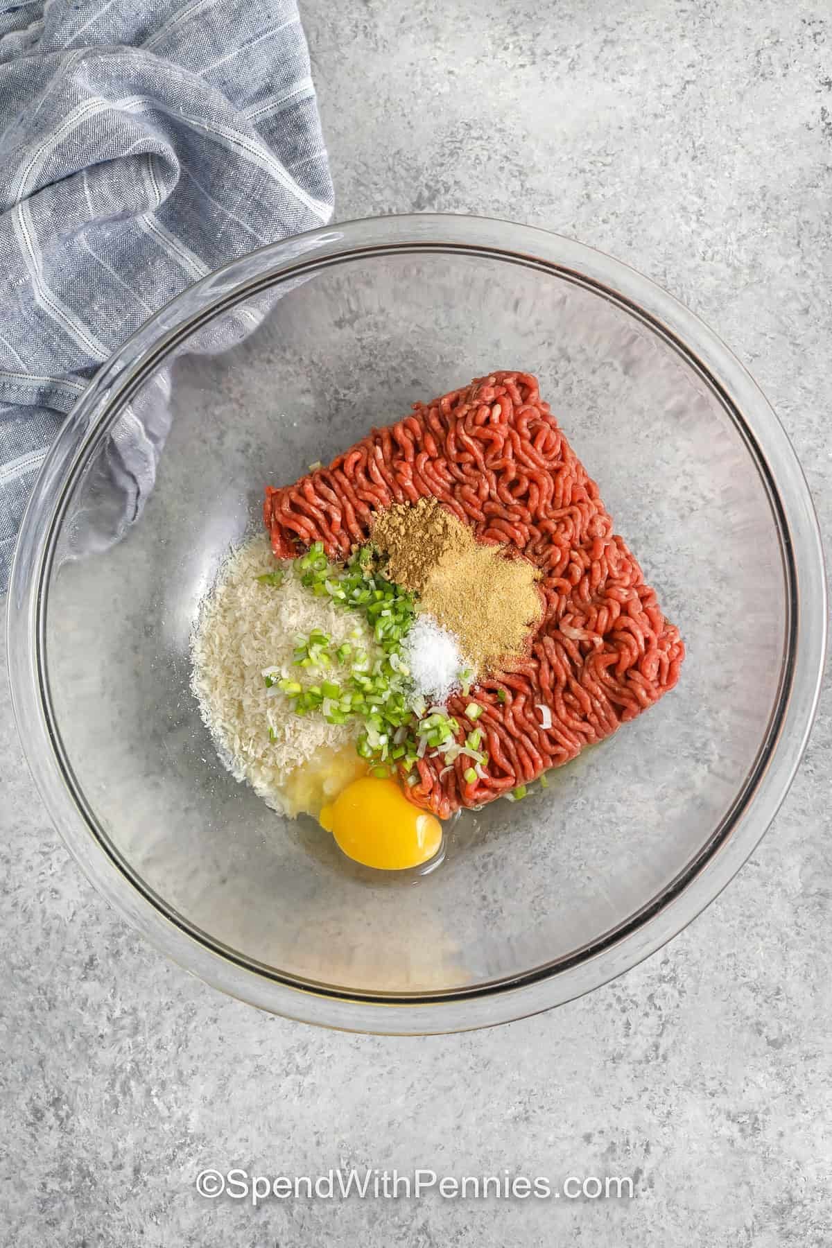 Firecracker meatballs are tender baked beef meatballs seasoned with ginger, garlic, and green onion, then drizzled with a creamy sriracha mayo firecracker sauce. The sauce is sweetened with honey and balanced with soy sauce for a savory finish. Serve over rice, in lettuce wraps, or as an appetizer with extra sauce for dipping. #spendwithpennies firecracker meatball ingredients in a bowl