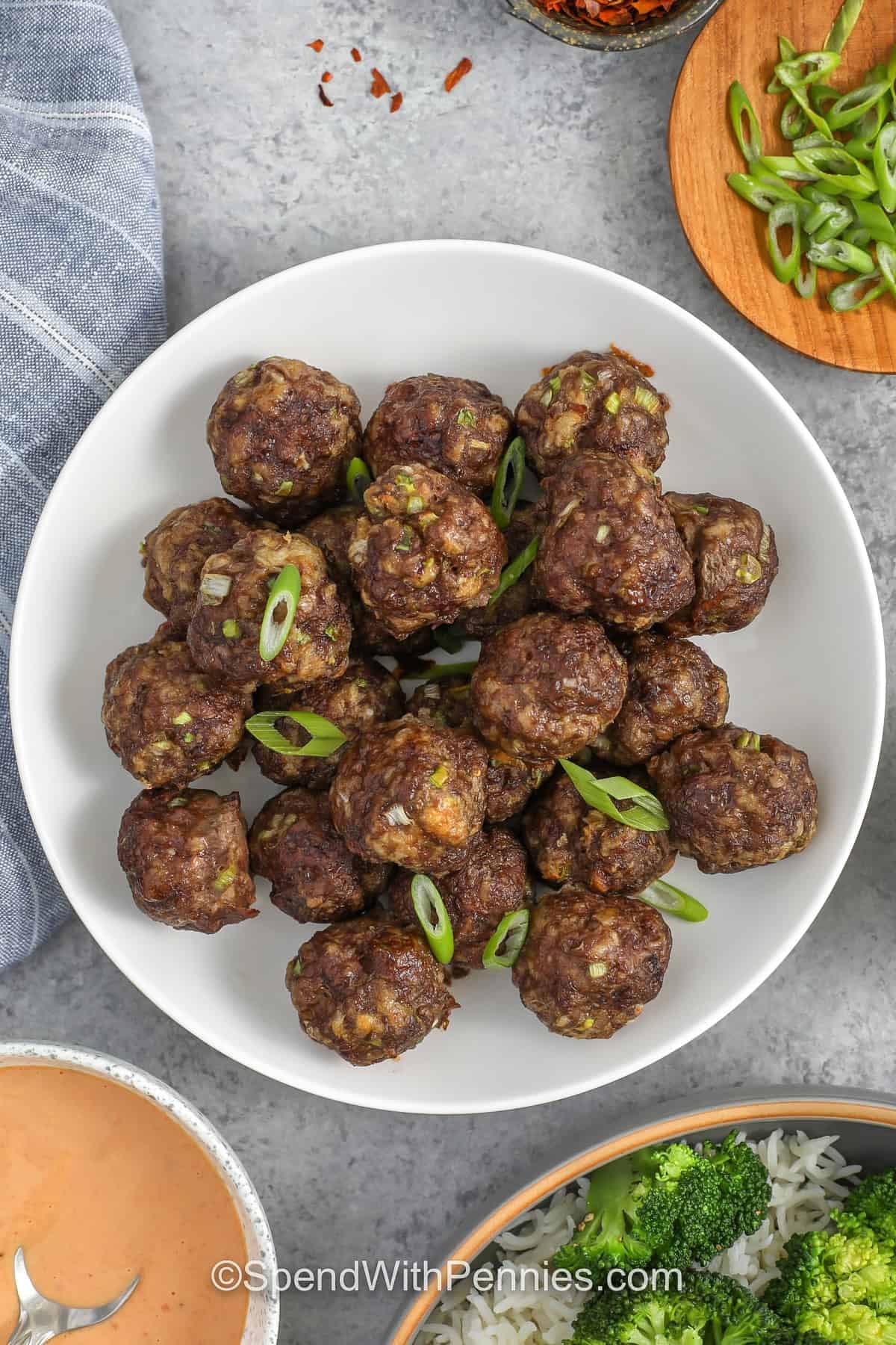 Make firecracker meatballs when you want sweet heat flavor with minimal dishes. The meatballs bake on a sheet pan while the creamy firecracker sauce whisks in one bowl using mayonnaise, sriracha, soy sauce, and honey. Top with sliced green onions and toasted sesame seeds for extra crunch and freshness. Serve as an appetizer platter or an easy dinner over rice. #spendwithpennies firecracker meatballs without sauce