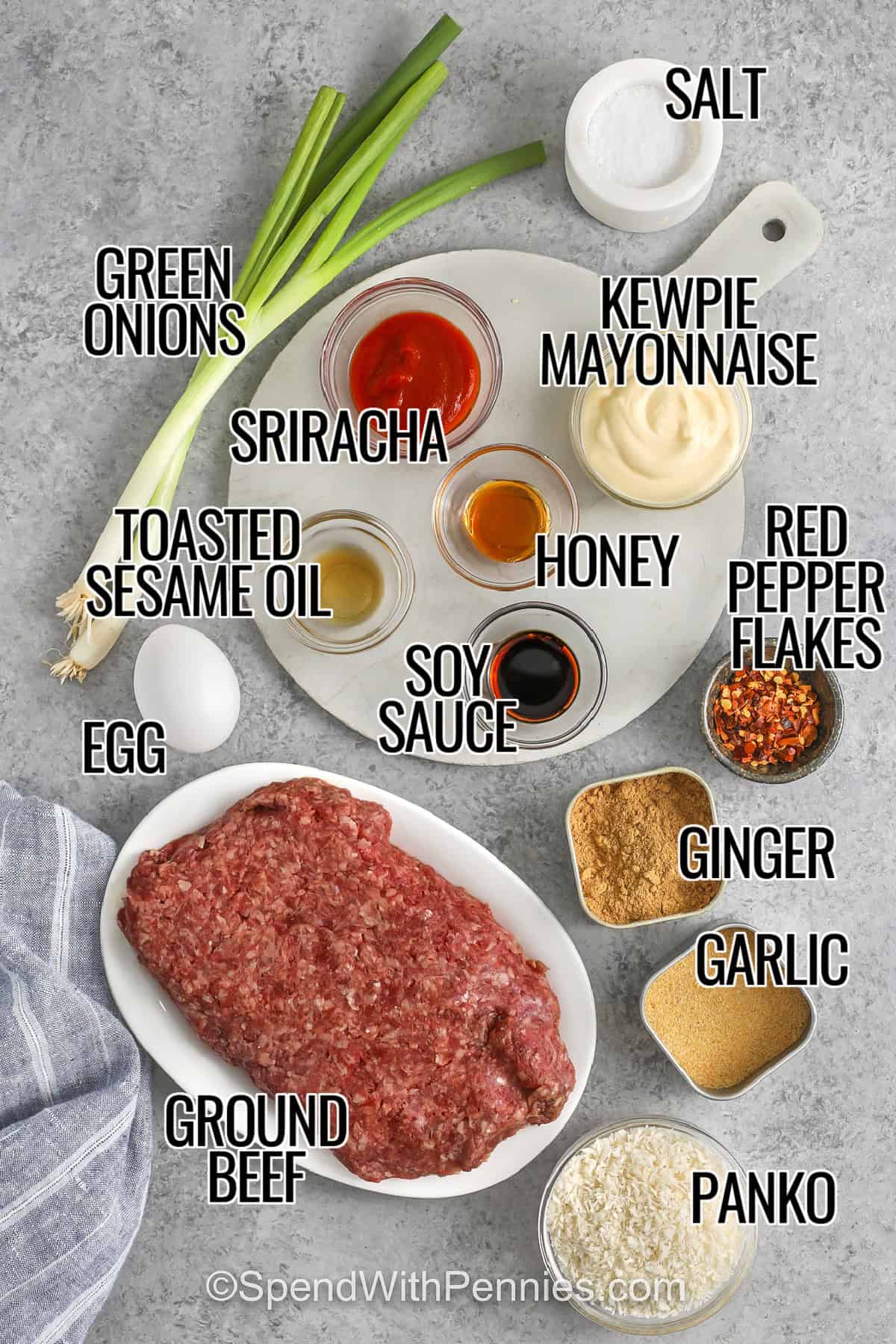 These firecracker meatballs are an easy baked meatball recipe with big Asian-inspired flavor. Ginger-garlic beef meatballs bake quickly, then get finished with a creamy sriracha mayo firecracker sauce that is sweetened with honey and deepened with soy sauce. Add sesame seeds and extra green onion for a simple, fresh garnish. These work for dinner bowls, sliders, or appetizers. #spendwithpennies labelled ingredients for firecracker meatballs: salt, green onions, kewpie mayonnaise, sriracha, honey, toasted sesame oil, soy sauce, red pepper flakes, ginger, garlic, egg, ground beef, and panko