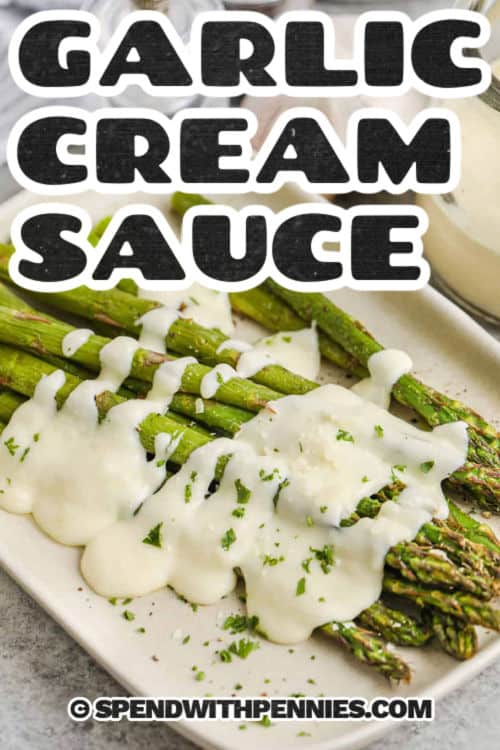 Garlic cream sauce poured over roasted asparagus on a plate with a title