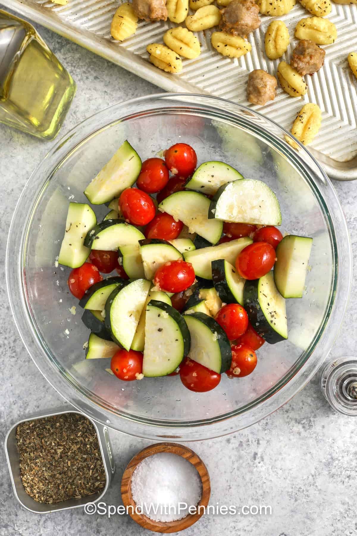 mixing vegetables with oil and seasonings to make Sheet Pan Gnocchi & Sausage