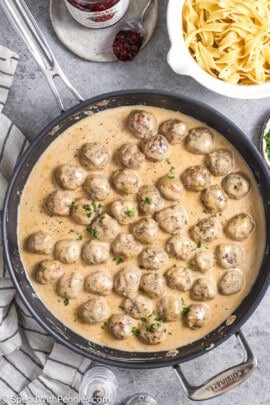 Cooked Swedish meatballs with parsley next to egg noodles