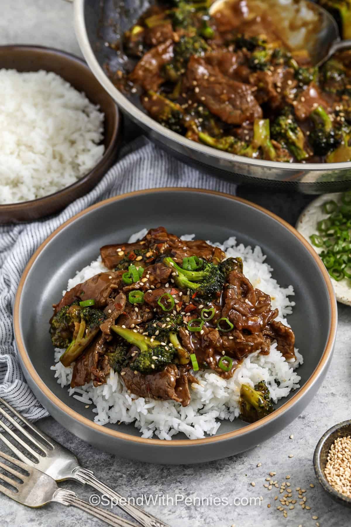 This homemade beef and broccoli recipe is a reliable dinner when you want something saucy, flavorful, and family friendly without spending all evening in the kitchen. This version uses steak, fresh broccoli, garlic, ginger, soy sauce, and brown sugar for a rich stir-fry finish. It is easy to serve over rice or noodles and works well for leftovers the next day. #spendwithpennies plated Beef and Broccoli Recipe with pan full in the back