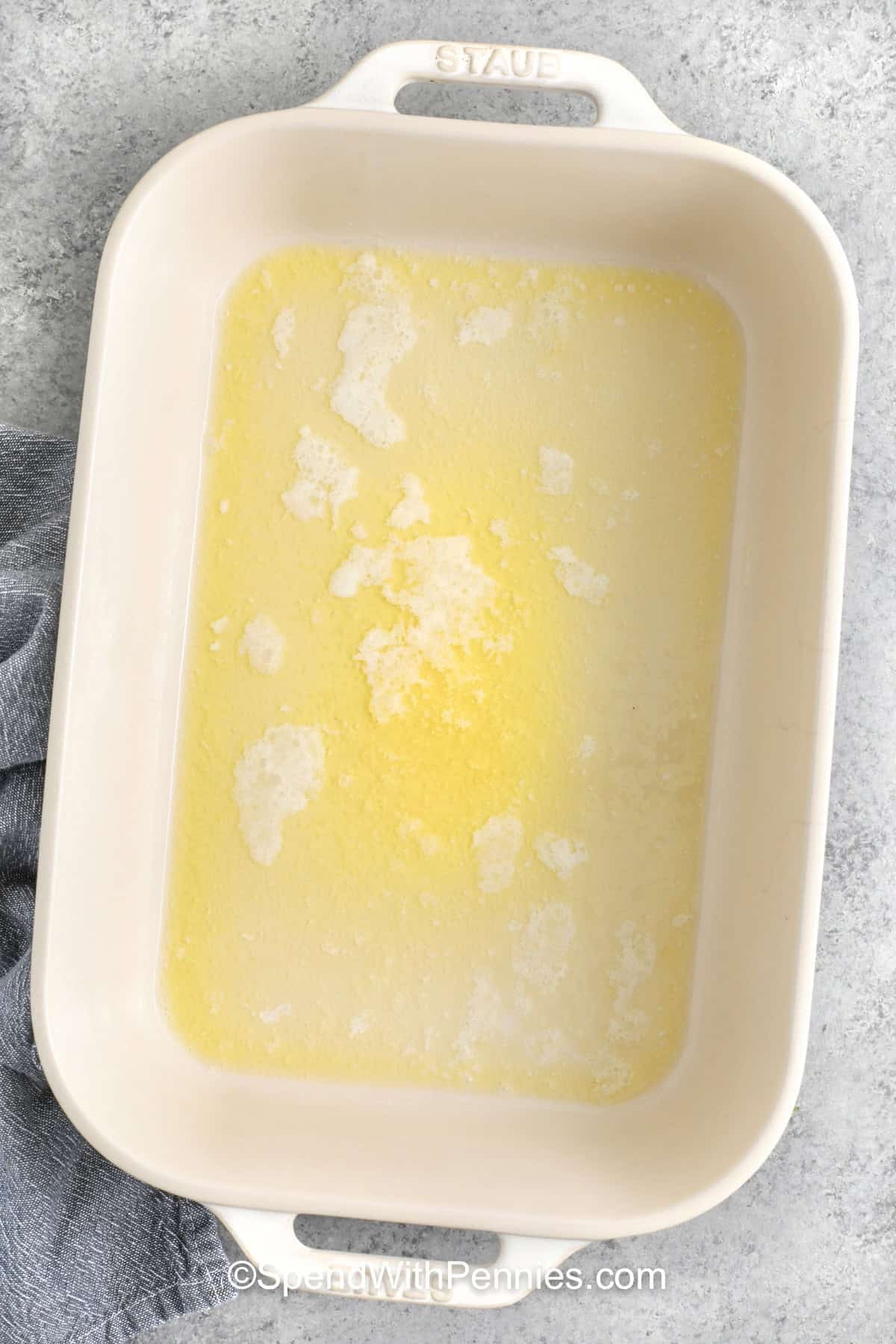 adding melted butter to dish to make Cheddar Chicken Cobbler
