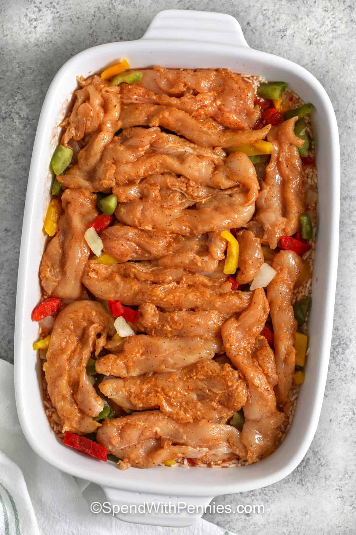 If you need a family-friendly dinner with very little prep, chicken fajita casserole is a smart choice. Frozen peppers and onions save chopping time, fajita seasoning adds instant flavor, and the oven does most of the work. The end result is tender chicken, fluffy rice, and melty cheese in every scoop, with classic fajita flavor that works well for meal prep and leftovers too. #spendwithpennies adding seasoned chicken to dish to make Chicken Fajita Casserole