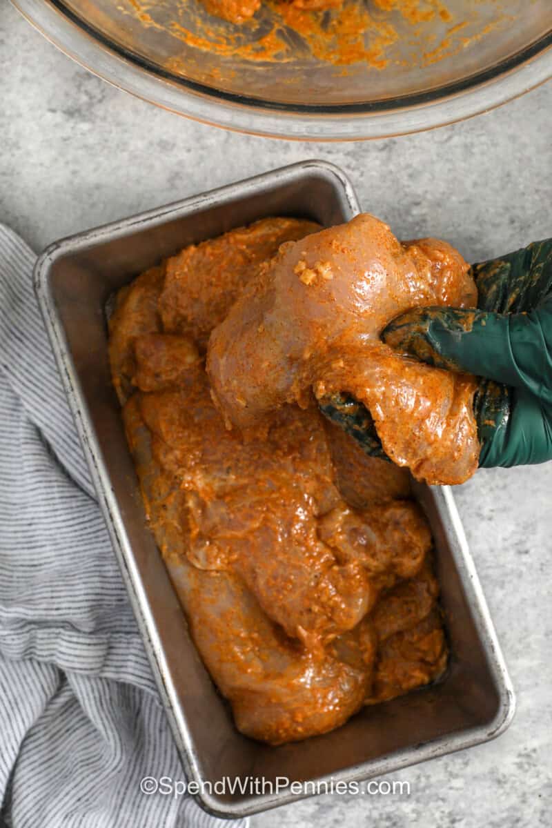 adding chicken to bottom of loaf pan to make Chicken Shawarma
