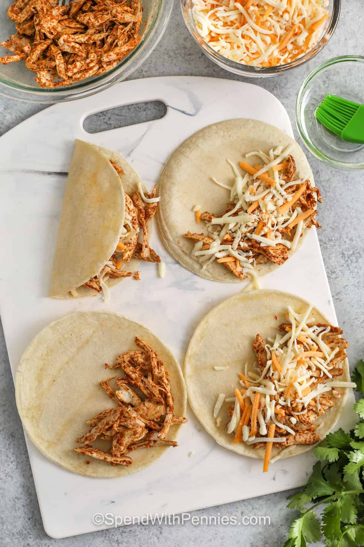 folding tacos over filling to make Crispy Chicken Tacos