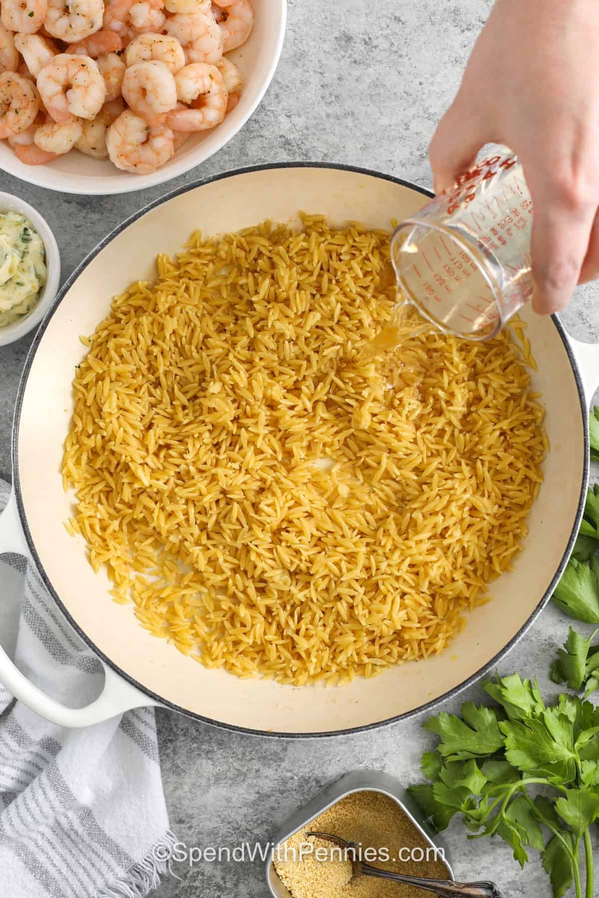 adding broth to orzo to make Garlic Butter Shrimp Orzo